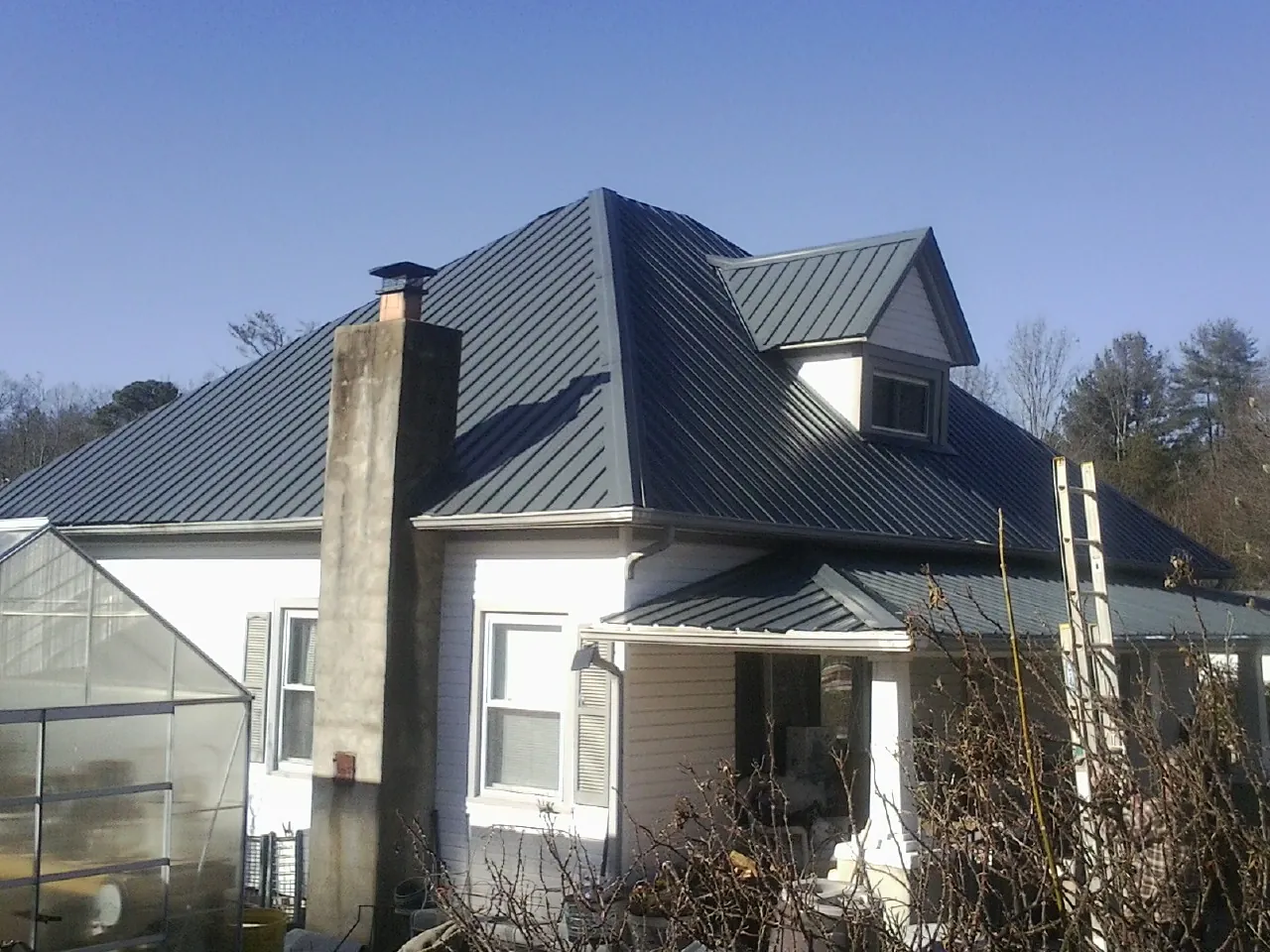 Dark blue standing seam metal roof on a white farmhouse with dormer — Slate & Tile Roof Repair by Roofing Brothers in Obion