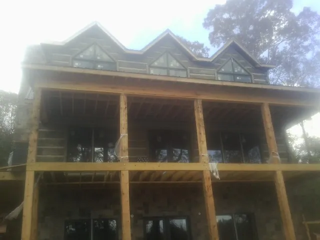 Dormers and porch framing on a large log home under construction — Roof Coating work by our crew in Obion