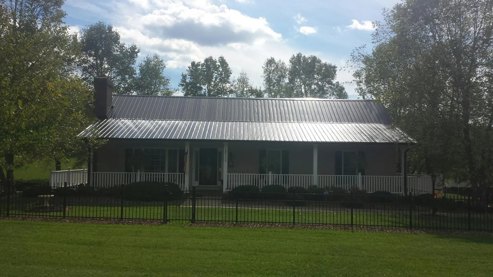 Gray metal roof on a brick ranch with a full width front porch — Gutter Guard Installation work by our crew in Obion